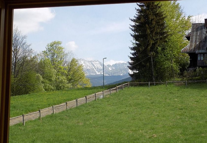 widok z okna apartamentu na góry i sąsiadującą łąkę